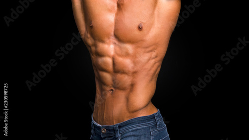 man with naked torso in blue jeans on black background.