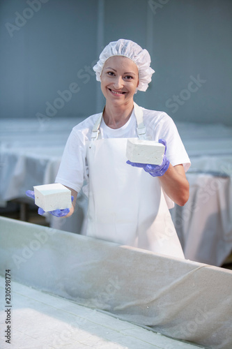 Female worker on white feta cheese production line in an industrial factory