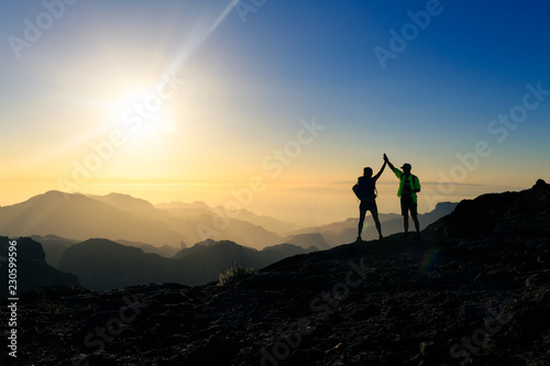 Couple hikers celebrating success concept in mountains