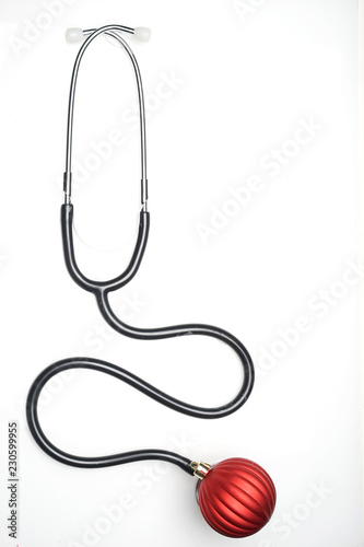 Celebrating Christmas in the healthcare industry. Top view of flat lay. Stethoscope with ornaments on a white background.