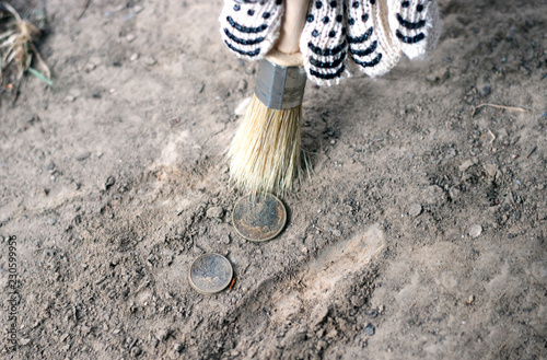  archeology female hand holds brush a tassel excavation of rare materials treasure hunt and archeology find rare Gold coins in sand 