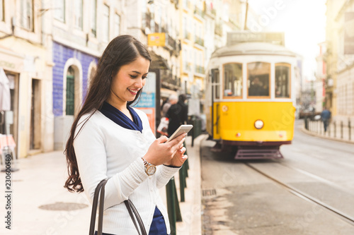 Woman tourist in Lisbon checking tram timetable on her smartphone