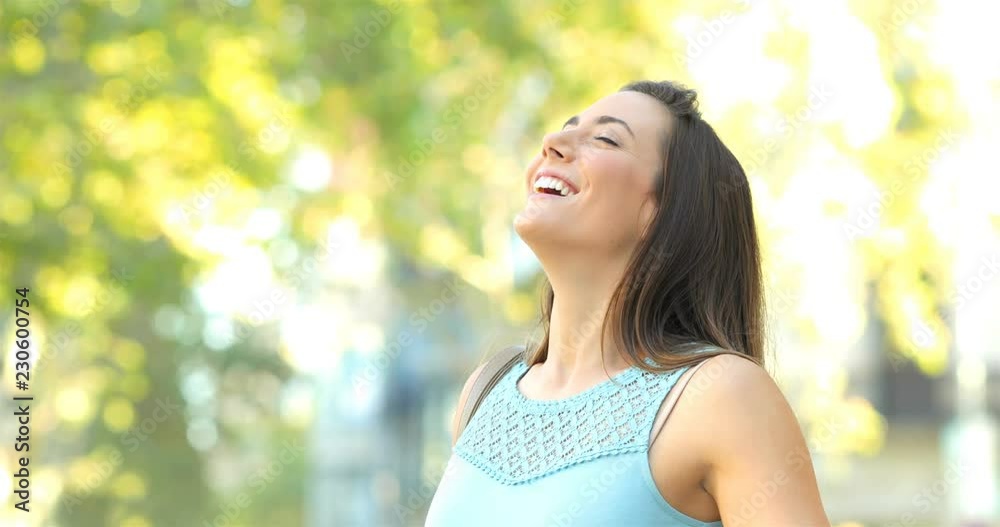 Happy woman breathing deep fresh air in the street with trees in the background Happy woman breathing deep fresh air in the street with trees in the background