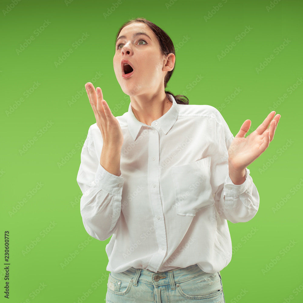 Wow. Beautiful female half-length front portrait isolated on green studio backgroud. Young emotional surprised woman standing with open mouth. Human emotions, facial expression concept. Trendy colors Wow. Beautiful female half-length front portrait isolated on green studio backgroud. Young emotional surprised woman standing with open mouth. Human emotions, facial expression concept. Trendy colors