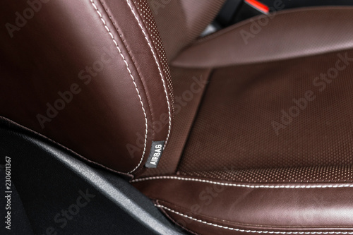 Modern luxury car brown leather interior. Part of leather car seat details with white stitching. Interior of prestige car. Comfortable perforated leather seats. Brown perforated leather. Car detailing © Aleksei