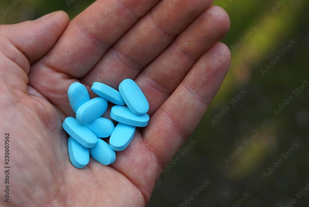 open hand with a bunch of blue pills open hand with a bunch of blue pills
