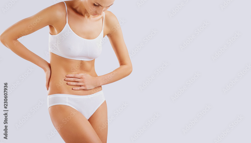 The concept of abdominal pain in a woman. The girl in underwear holds a  stomach with a hand from pain. Stock Photo