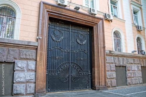 large old black gate with a forged pattern on the wall of a building with windows