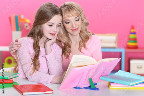 Portrait of beautiful girl reading book with mother