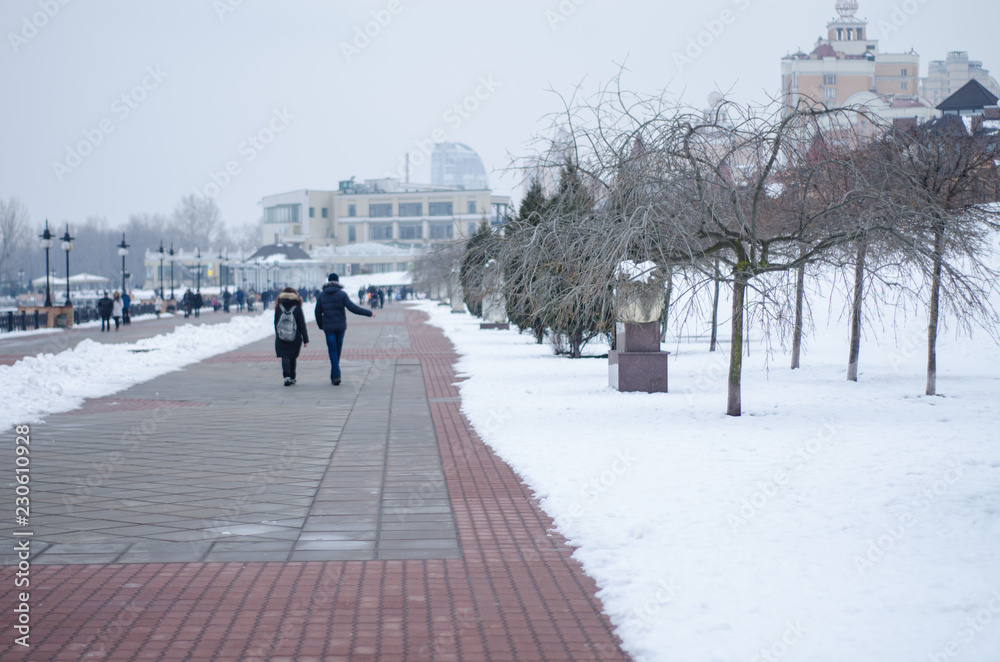 A couple walking along the waterfront in winter A couple walking along the waterfront in winter