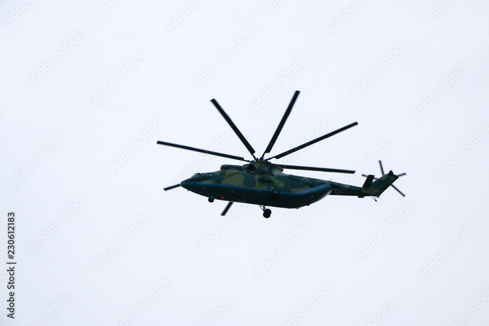 a large military helicopter hovers in the sky. A camouflaged helicopter flies at high speed. a large military helicopter hovers in the sky. A camouflaged helicopter flies at high speed.