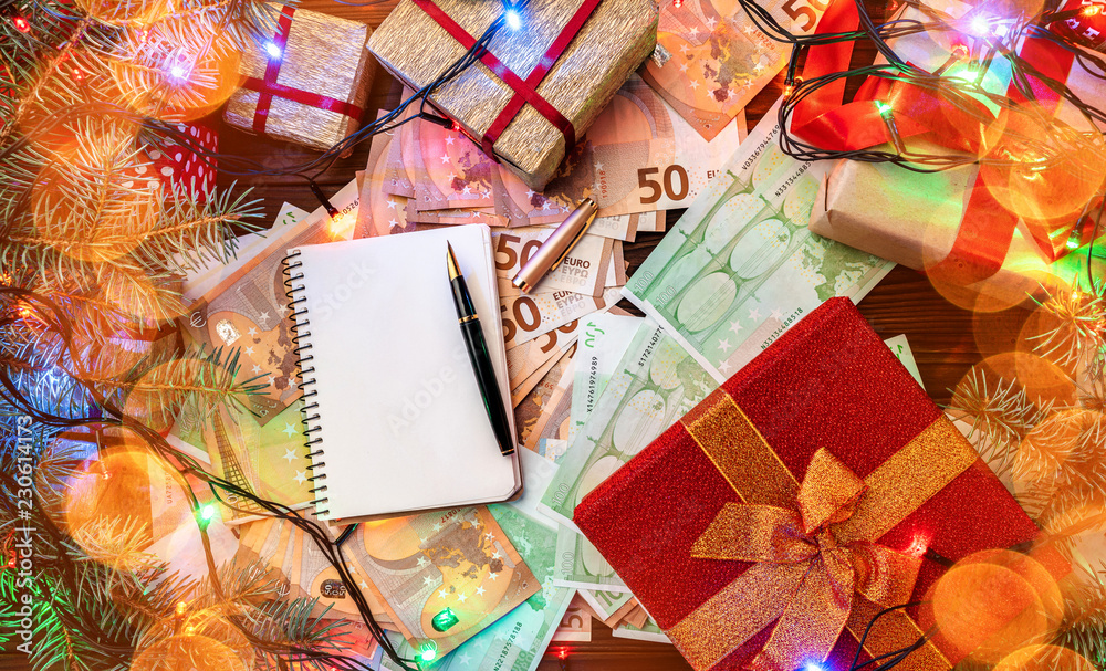 Christmas background. Gifts for loved ones. Money of different values. Space for your text in the notebook. Top view. Effect of light blips. Christmas background. Gifts for loved ones. Money of different values. Space for your text in the notebook. Top view. Effect of light blips.