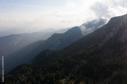 Aerial photography over big mountain forest. Sunset over the forest. Foggy valley at the sunrise. Golden hour over the forest with mist. Beautiful aerial landscape. Drone shots over the foggy forest. 