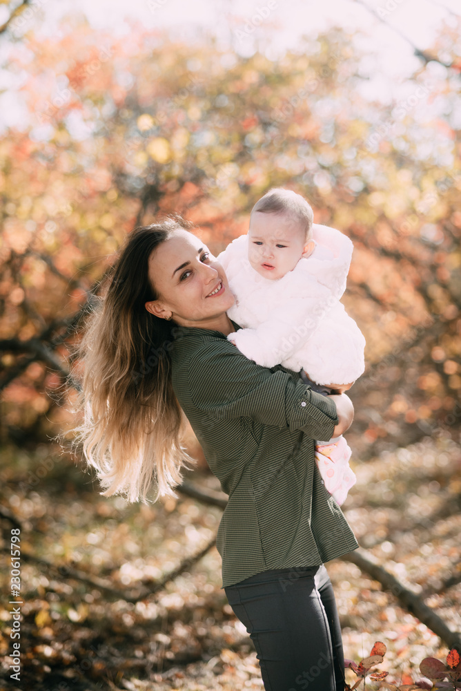 Young mother with little girl in autumn forest with a beautiful colored background Young mother with little girl in autumn forest with a beautiful colored background