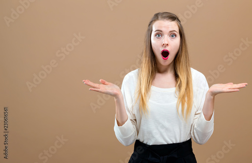 Surprised young woman posing on a brown background