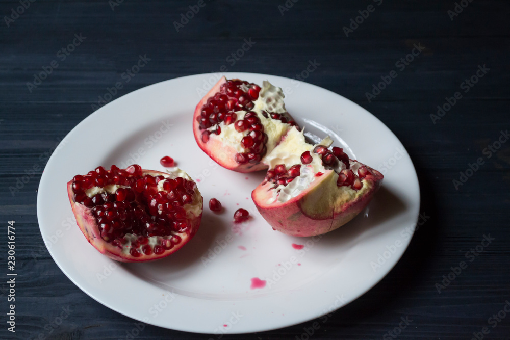 Pomegranate on a white plate. Close up. Pomegranate on a white plate. Close up.