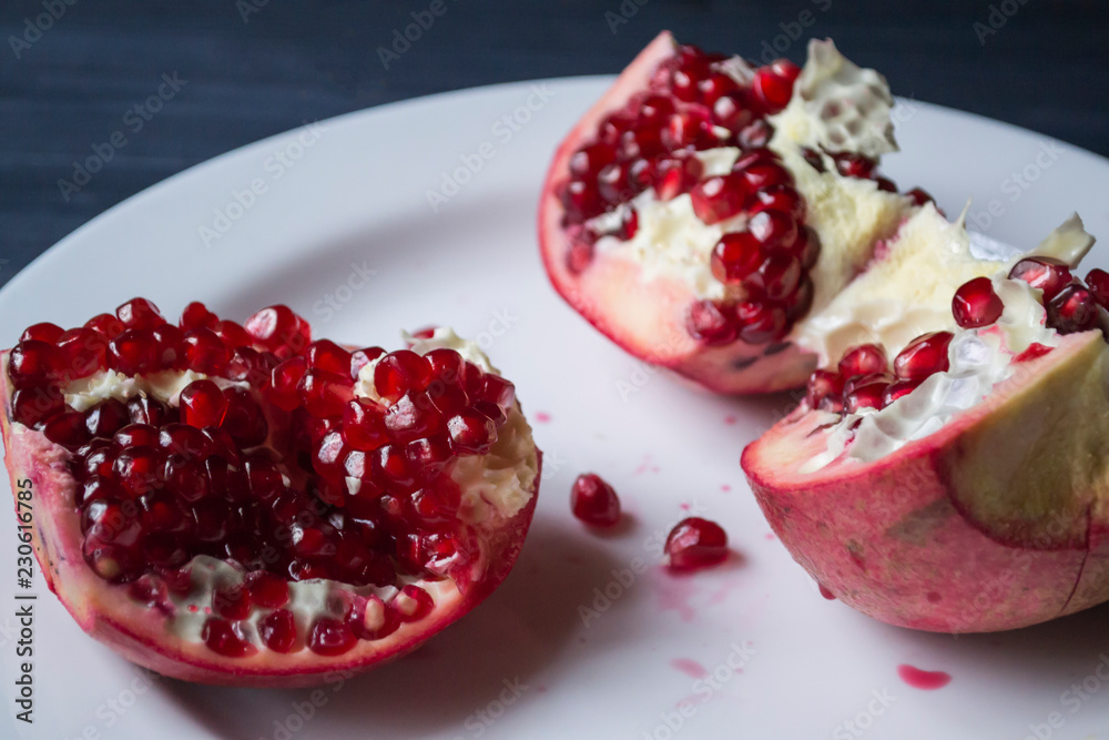 Pomegranate on a white plate. Close up. Pomegranate on a white plate. Close up.