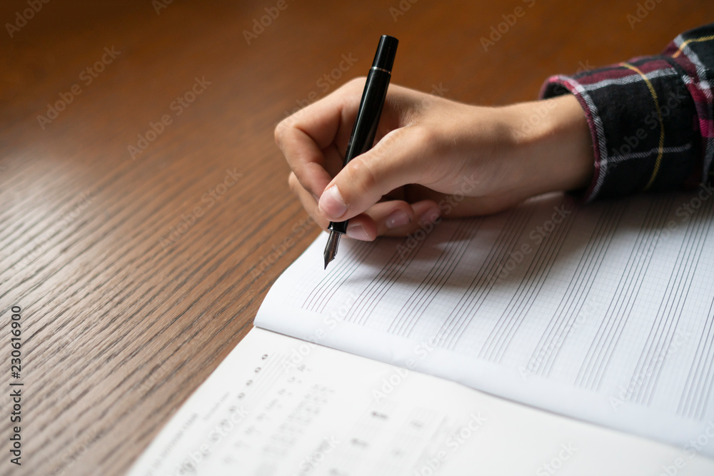 close up student hands write down music notes on class in school f close up student hands write down music notes on class in school f