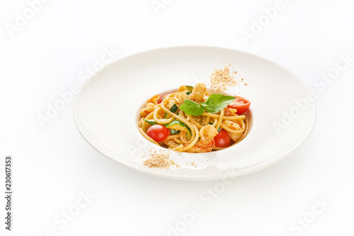 Spaghetti with shrimps, cherry tomatoes, zucchini and basil on white background