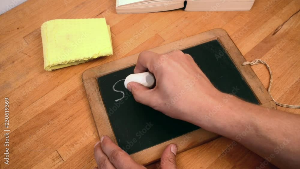 person writing schools out on a chalkboard