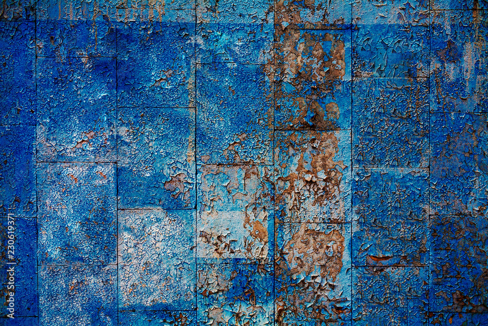 Grungy tiled wall covered with peeleng blue paint