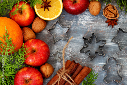 Christmas background - Apples ,orange, cinnamon sticks and walnuts with cypress branches 