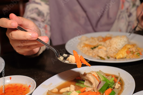 Girls hand scooping Chicken Paprik on plate over dining table