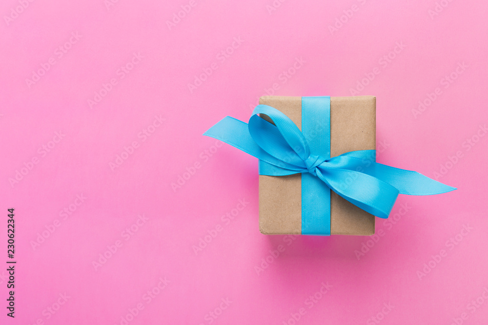 gift wrapped and decorated with blue bow on pink background with copy space. Flat lay, top view gift wrapped and decorated with blue bow on pink background with copy space. Flat lay, top view