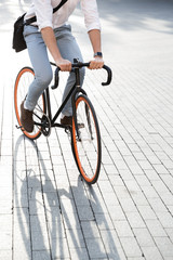 Photo of handsome man 30s wearing formal clothing, riding on bicycle on city street
