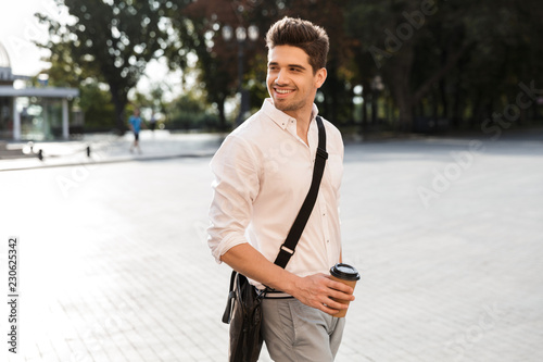 Cheerful businessman dressed in shirt walking outdoors