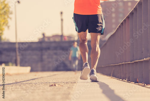 Strong legs of young runner running jogging in city street at sunset in city training workout