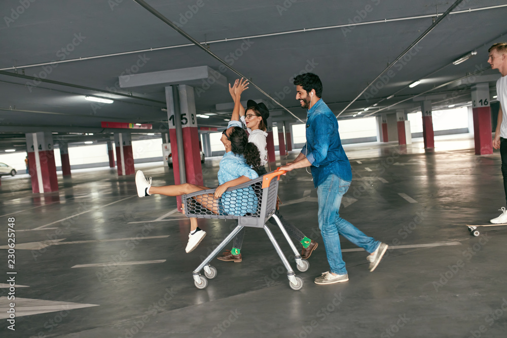 Fototapeta premium Young People Having Fun, Racing On Shopping Trolley At Parking