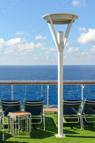 View from the deck of a cruise ship in the ocean. Seating area for passengers, chairs and sun loungers. Sunbathe.