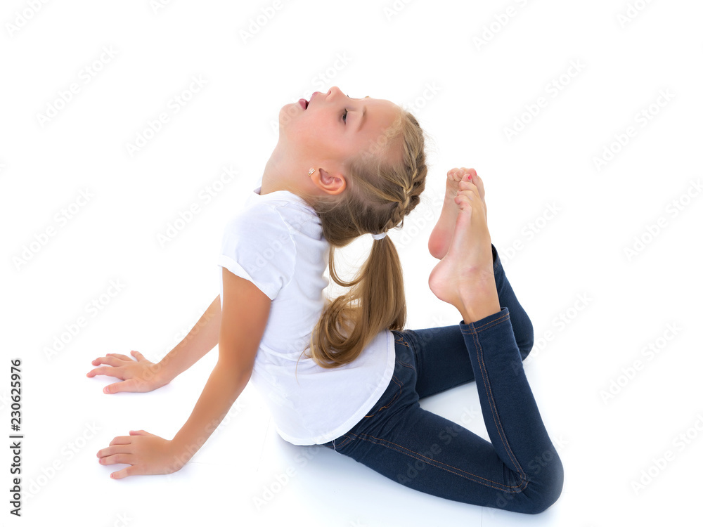The little gymnast perform an acrobatic element on the floor.