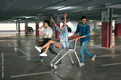 Young People Having Fun, Racing On Shopping Trolley At Parking