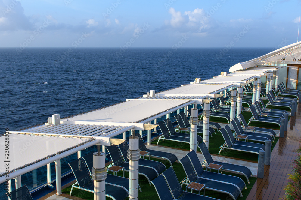 View from the deck of a cruise ship in the ocean. Seating area for passengers, chairs and sun loungers. Sunbathe.