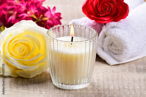 white candle with yellow flower on wooden background, scented candle, spa composition. photo