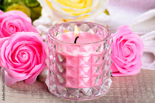 pink rose candle with flowers and towel on wooden background, photo