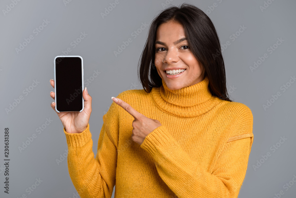 Amazing excited woman posing isolated over grey wall background showing display of mobile phone. Amazing excited woman posing isolated over grey wall background showing display of mobile phone.