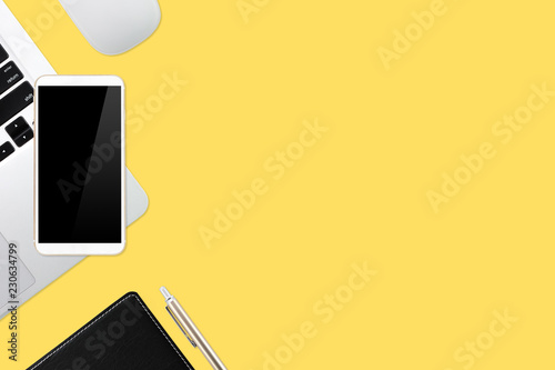 flat lay workspace table with laptop computer, office supplies, coffee cup, tablet and cell phone on yellow pastel background