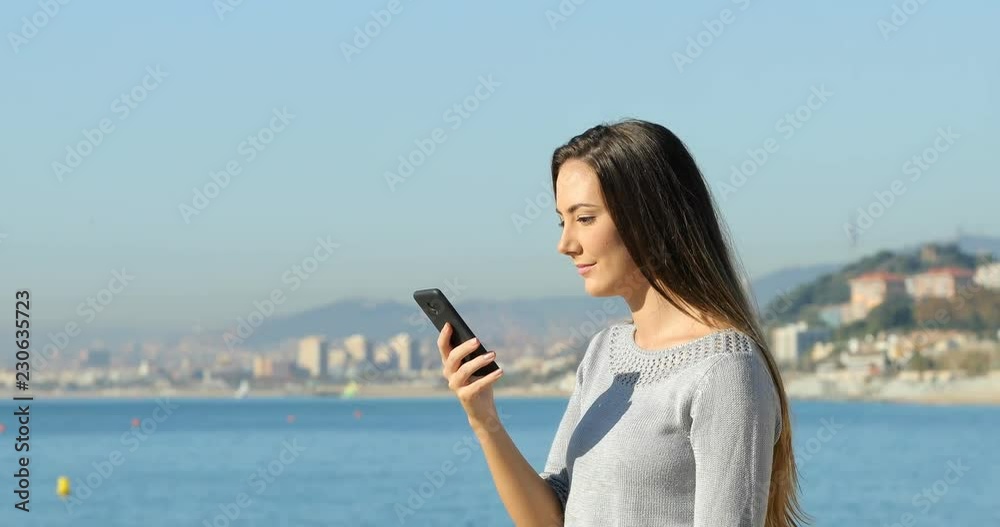 Side view portrait of a excited girl celebrating online good news from a smart phone jumping on the beach Side view portrait of a excited girl celebrating online good news from a smart phone jumping on the beach