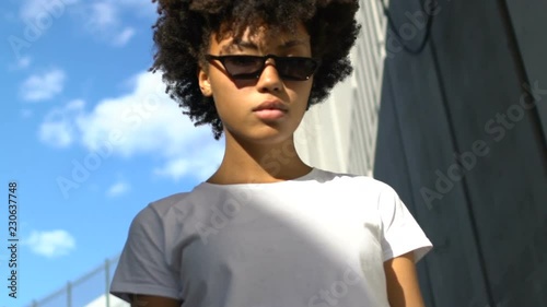 Self-confident woman in dark sunglasses posing for camera, urban style, fashion