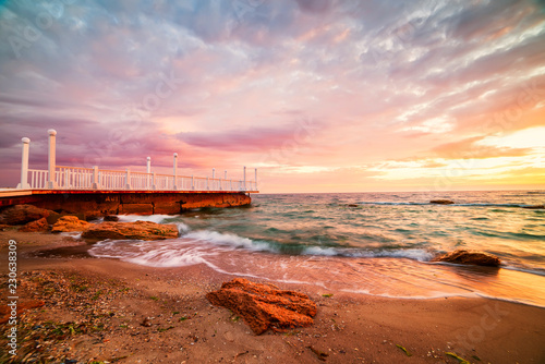 Bright colorful sunrise at the pier by the sea.
