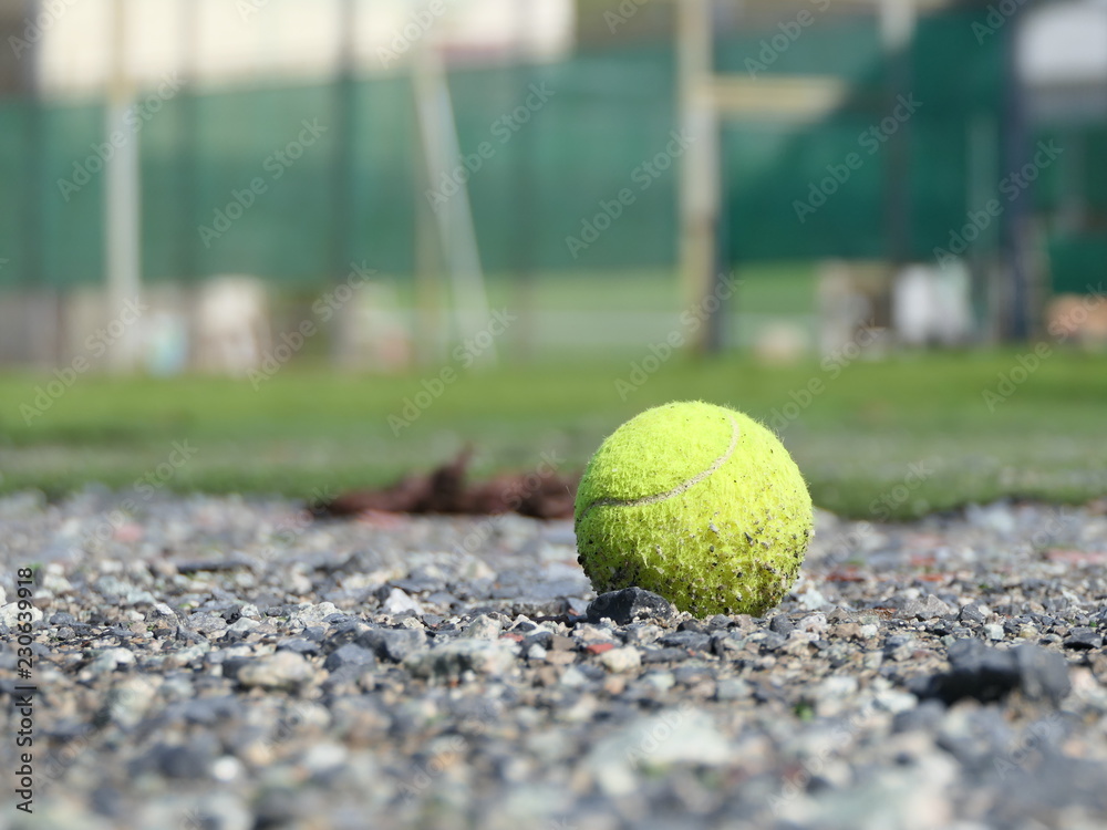 Close up a dirty green tennis ball on Gravel floor.