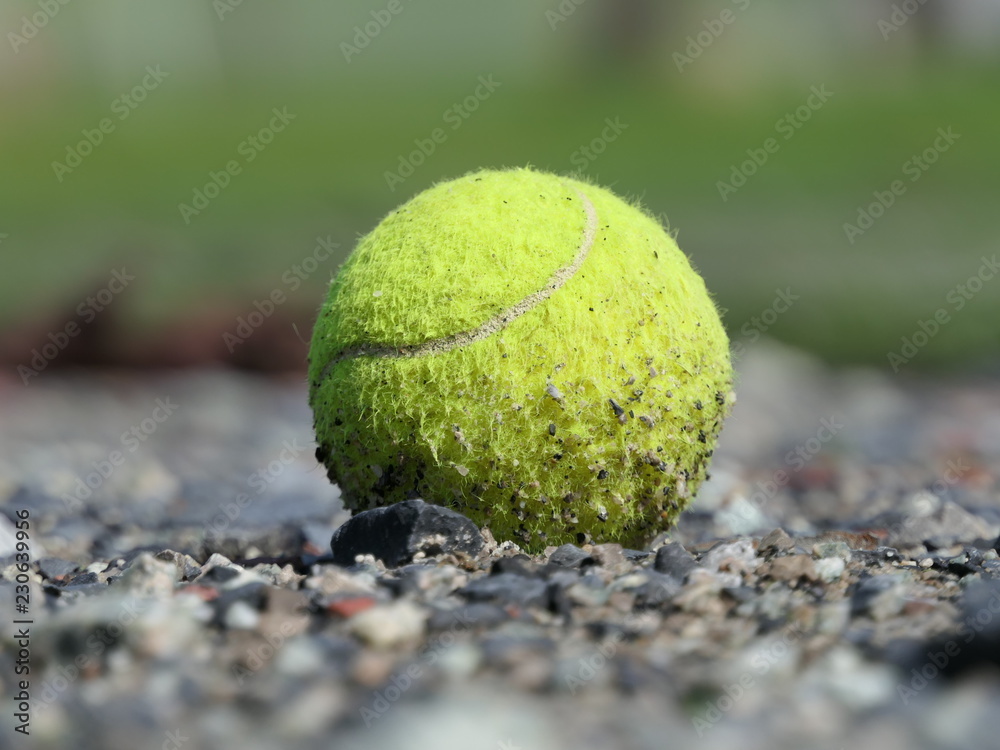 Close up a dirty green tennis ball on Gravel floor.
