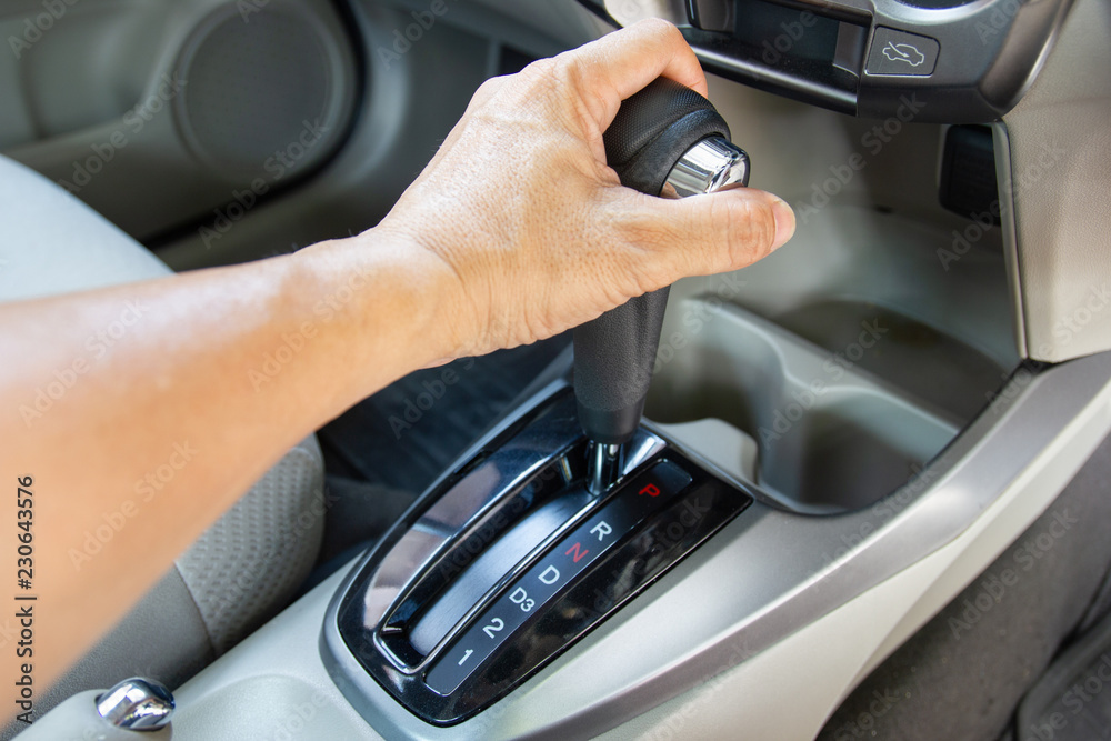 Fototapeta premium Men's arm hold control auto gear for car shifting into P will try to engage the parking pawl to prevent the transmission