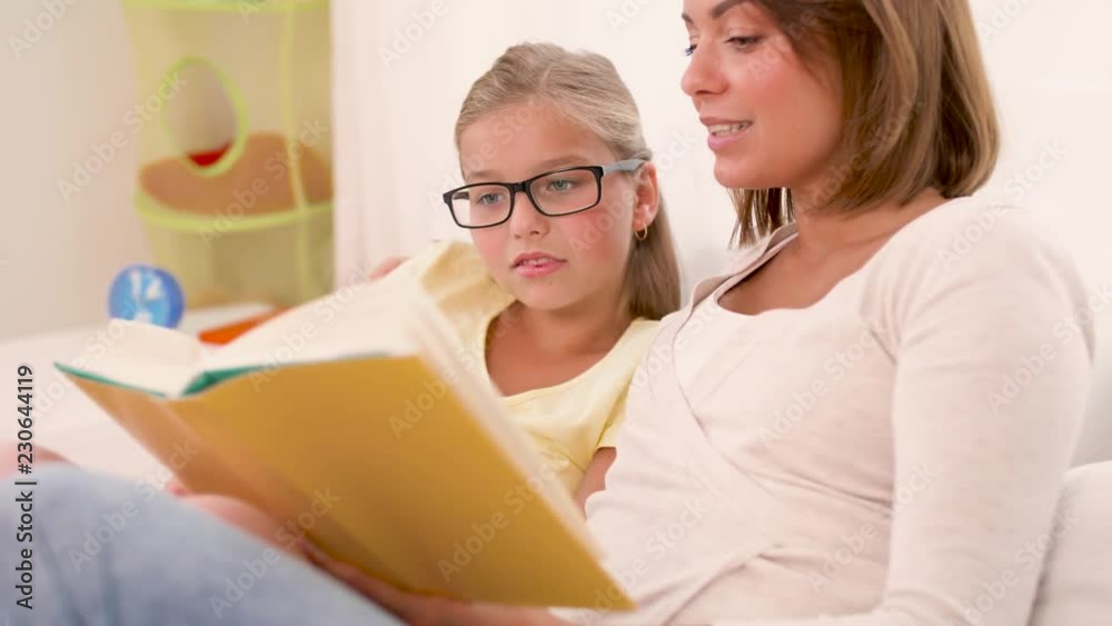 people, family and education concept - happy daughter with mother reading book at home people, family and education concept - happy daughter with mother reading book at home