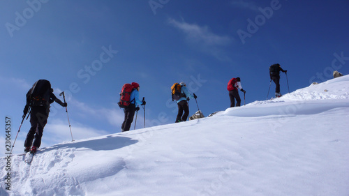 a group of backcountry skiers hike and climb to a remote moutain peak in Switzerland