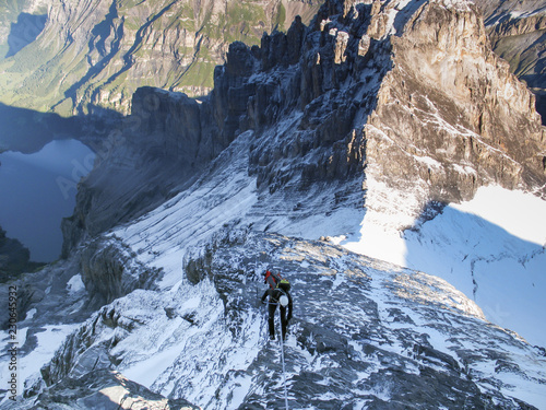 mountain climber rappelling from a high rocky mountain peak in the Swiss Alps near Kandersteg photo