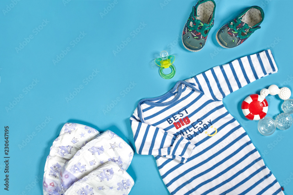 Baby clothing, toiletries, toys and health care accessories on blue background.